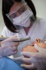 Dentista examinando paciente com ferramentas odontológicas na clínica — Fotografia de Stock