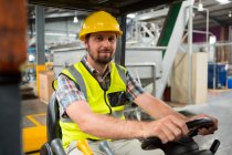 Portrait of young male worker driving forklift in warehouse — Stock Photo