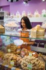Жінка-магазин, що обслуговує турецьку випічку в тарілці за лічильником в магазині — стокове фото