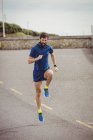 Handsome athlete running on country road — Stock Photo