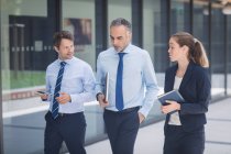 Confident businessman walking with colleagues outside office building — Stock Photo
