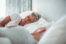 Seniorenpaar schläft auf Bett im Schlafzimmer — Stockfoto