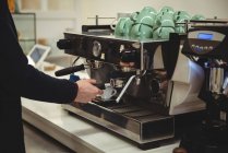 Рука человека держит портативный фильтр под кофеваркой в кофейне — стоковое фото