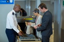 Ufficiale di sicurezza aeroportuale che controlla la borsa del pendolare in aeroporto — Foto stock