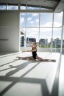 Балерина растягивается на полу во время репетиции балета в студии — стоковое фото