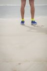 Низкая часть спортсмена стоит на песчаном пляже — стоковое фото