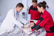 Médecin et ambulanciers examinant un patient aux urgences de l'hôpital — Photo de stock