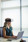 Executivo de negócios usando headset realidade virtual e trabalhando no laptop no escritório — Fotografia de Stock