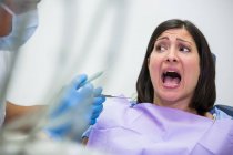 Жінка-пацієнтка боїться під час стоматологічного огляду в стоматологічній клініці — стокове фото