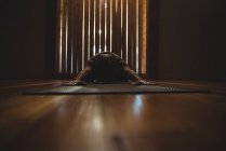 Femme pratiquant le yoga dans un studio de fitness sombre — Photo de stock