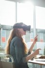 Ejecutiva femenina usando auriculares de realidad virtual en la oficina - foto de stock