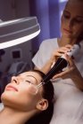 Жіночий дерматолог, що проводить лазерну епіляцію на обличчі пацієнта в клініці — стокове фото