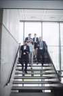 Gente de negocios segura de pie en la escalera en la oficina - foto de stock