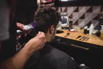 Hombre consiguiendo pelo recortado por estilista con trimmer en peluquería - foto de stock