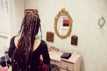 Вид сзади на косметолога, укладку волос клиентов в магазине дредов — стоковое фото