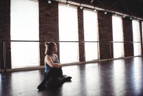 Молодая танцовщица выполняет упражнения на растяжку в танцевальной студии — стоковое фото