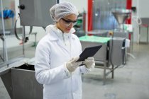 Technicienne utilisant une tablette numérique à l'usine de viande — Photo de stock