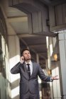Empresário falando no celular enquanto caminha no corredor do prédio de escritórios — Fotografia de Stock