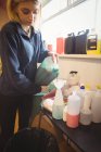Donna che versa shampoo per cani in una bottiglia al centro di cura del cane — Foto stock