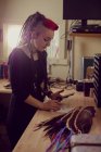 Cabeleireiro feminino usando telefone celular e fazendo anotações na loja dreadlocks — Fotografia de Stock