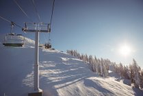 Remonte en la estación de esquí contra el cielo azul con gente de fondo - foto de stock