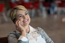 Businesswoman talking on mobile phone in waiting area at airport terminal — Stock Photo