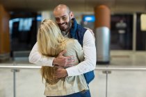 Allegra coppia che si abbraccia in sala d'attesa al terminal dell'aeroporto — Foto stock