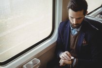 Geschäftsmann kontrolliert Uhrzeit während Zugfahrt — Stockfoto