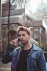 Чоловік розмовляє по мобільному телефону, стоячи на вулиці — стокове фото
