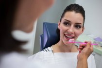 Dentista segurando escova na frente do paciente na clínica — Fotografia de Stock