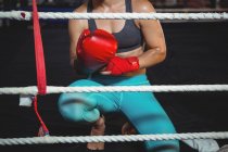 Mulher boxeadora usando luvas de boxe no ringue de boxe no estúdio de fitness — Fotografia de Stock