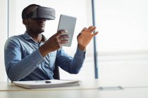 Керівник бізнесу, використовуючи гарнітуру віртуальної реальності та цифровий планшет в офісі — стокове фото