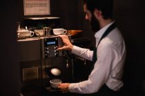 Camarero haciendo taza de café de la máquina de café expreso en el bar - foto de stock