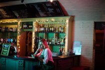 Nachdenkliche Kellnerin sitzt am Tresen in Bar — Stockfoto