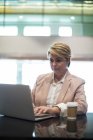 Businesswoman using laptop in waiting area at airport terminal — Stock Photo