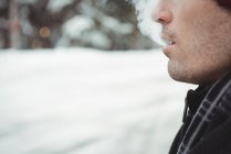 Крупним планом чоловік, що видихає сигарету дим взимку — стокове фото