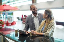 Smiling couple interacting with each or in waiting area at airport terminal — Stock Photo