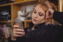 Nachdenkliche Frau nutzt Handy zu Hause — Stockfoto