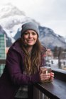 Retrato de mulher em roupas de inverno segurando copo de cerveja no terraço ao ar livre — Fotografia de Stock