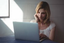 Красива жінка використовує ноутбук у вітальні вдома — стокове фото