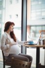 Pregnant businesswoman using laptop in office cafeteria — Stock Photo