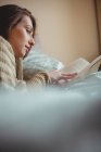 Красивая женщина читает книгу на кровати дома — стоковое фото