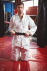 Confident karate player tying belt in fitness studio — Stock Photo