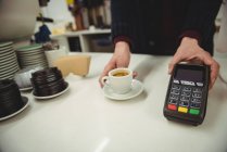 Руки человека, держащего ЭДС-машину и чашку кофе в кафе — стоковое фото