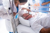 Doctora poniendo máscara de oxígeno en la cara del paciente en el hospital - foto de stock