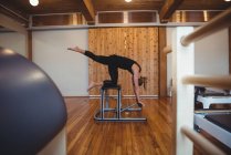 Vista lateral da mulher praticando pilates no estúdio de fitness — Fotografia de Stock