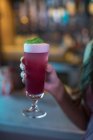 Femme tenant un verre de cocktail rose au bar — Photo de stock