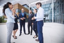 Group of cheerful businesspeople interacting outside office building — Stock Photo