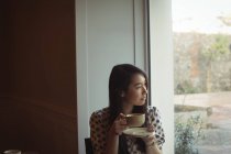 Mulher atenciosa tendo xícara de café perto da janela no café — Fotografia de Stock