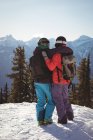 Rear view of two skiers standing together with arm around on snow covered mountain — Stock Photo